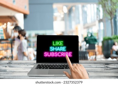 Hand point on a button of like, share, or subscribe on a laptop computer, in a cafe. - Powered by Shutterstock