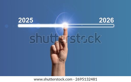 Hand pointing to digital loading bar symbolizing transition from 2025 to 2026. Modern blue technology background representing progress, business strategy, and future growth. Virtual countdown concept