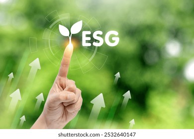 A hand is pointing to a green leaf with the letters ESG. Concept of growth and progress, as the hand is reaching up towards the leaf. The green color of the leaf - Powered by Shutterstock