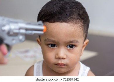 Hand Pointing Gun At The Head Of Child