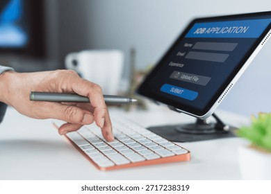 Hand pointing at a keyboard while submitting an online job application form displayed on a tablet in a bright workspace.