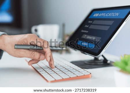 Hand pointing at a keyboard while submitting an online job application form displayed on a tablet in a bright workspace.