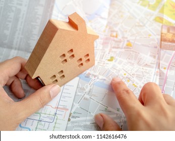 Hand Pointing On The Map And Wooden House Top View. Property Investment And Family Concept.