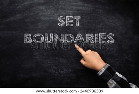 A hand pointing to the word set boundaries on a blackboard. Concept of setting limits or boundaries in a situation