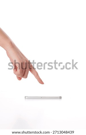 Hand points at a flat object on a white surface with focus on a finger touching the item