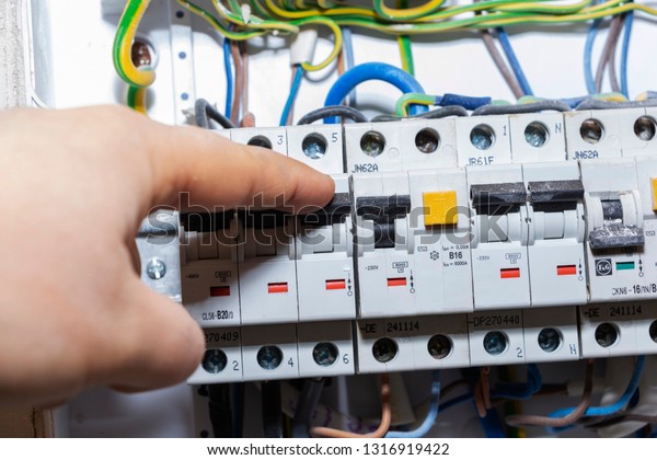 The hand points to a\
fuse in the power meter. The man disables the current fuses, the\
safety concept of the power suppression, and the protection of\
electrical devices