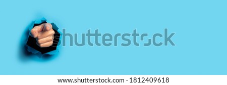 Hand points to something on a blue background. Gesture look at this, pay attention