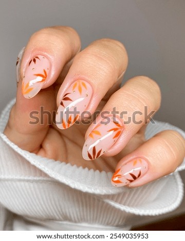 A hand with polished nails featuring simple, youthful, and modern autumn floral patterns. Autumn nails. Nails art design. Basic manicure. Acrylic nails