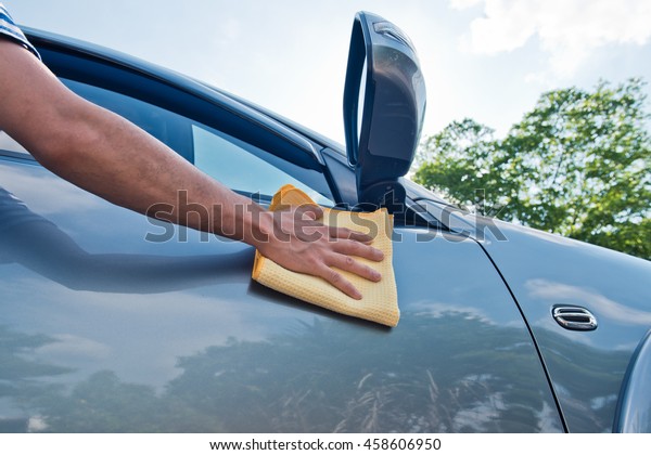 Hand polishing the car hood ,using microfiber cloth for\
cleaning 