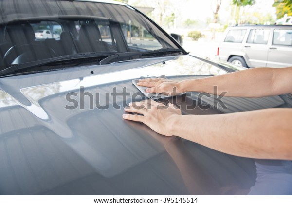 Hand polishing dirt at the car hood\
,worker using fabric for cleaning and rub\
waxing\
