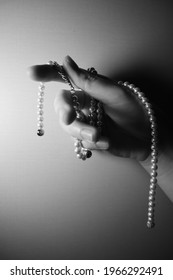 A Hand Pose With A Pearl Necklace Hanging In The Black And White Tone.