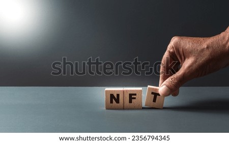 hand posing wooden cubes with the letters N F T , concept of non fungal tokens , on grey background , with copy space . Foto stock © 