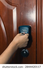Hand is positioned to input a code on a digital keypad lock attached to a wooden door, highlighting security technology in a home environment