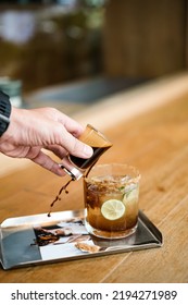 Someone’s Hand Pouring Coffee Into Soda Glass