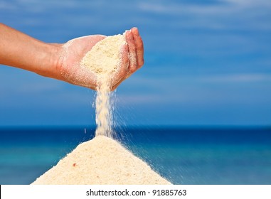 Hand Is Pouring Coral Sand On A Beach