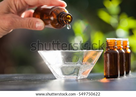 hand pouring essential oil in a bowl