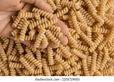 Hand Pouring Gluten Free Cornmeal Pasta. Spiral Raw Macaroni From Blend Of Corn And Rice Flour Rotating On Turntable. Top View. Close Up. Uncooked Rotini Pasta Is Spinning. Food Background. Ad