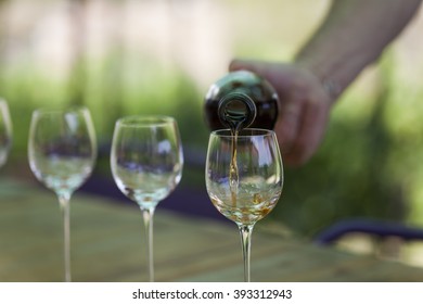 Hand Pouring Liquor Into Glasses During A Vineyard Tour