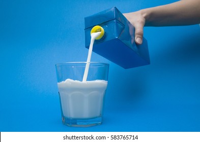 Hand Pouring Milk From A Carton Into Glass