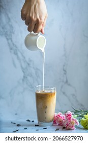 Hand Pouring Milk Into A Cup Of Iced Tea.