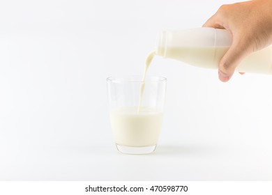 Hand Pouring Milk Into A Glass On A White Background.