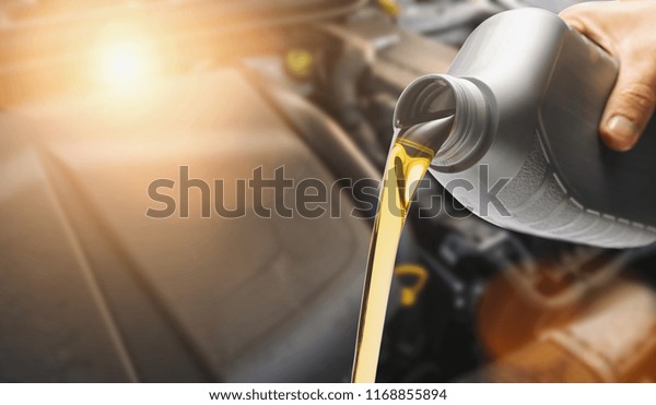Hand Pouring oil to car engine, Fresh oil poured\
during an oil change to a\
car.