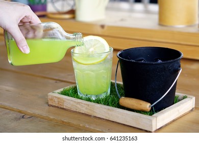 Hand Pouring Punch Lemon Juice With Soda In Glass Decorated With Slice Of Lemon - Summer Cocktail Or Tropical Mocktail.