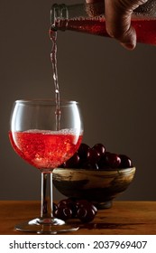 A Hand Pouring Red Juice In A Glass