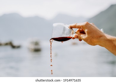 Hand Pouring Red Wine From A Glass