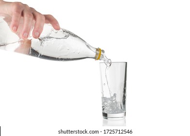 Hand Pouring Soda Water From Plastic Bottle Into Glass On White Background