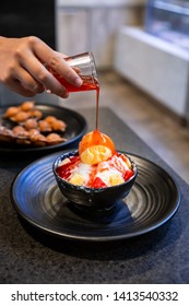 Hand Pouring Strawberry Sauce On Bingsu, A Korean Shaved Ice Dessert With Sweet Toppings Such As Vanilla Ice Cream, Cheese Cube And Sweetened Condensed Milk. It's Very Popular Dessert.