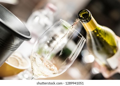 Hand Pouring White Wine In Glass In Italian Restaurant. Close Up View.