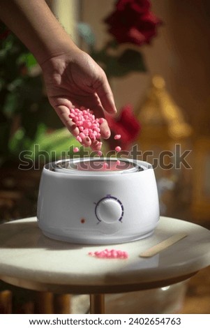Hand pours har wax beans in wax warmer