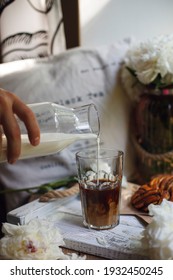 Hand Pours Milk From A Glass Transparent Bottle Into A Glass With Ice Coffee. Macro Photo Of Coffee Ritual. Cold Brew Coffee. Summer Beverage