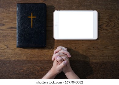 Hand praying with bible and blank tablet  on wooden table, Church online Sunday services new normal concept, Home church during quarantine coronavirus Covid-19, Study Bible worship online concept