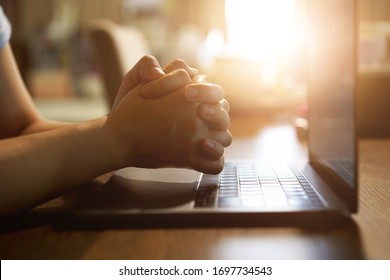 Hand praying with laptop, Church online Sunday services concept, Home church during quarantine coronavirus Covid-19, Hands folded in prayer concept for faith. - Shutterstock ID 1697734543