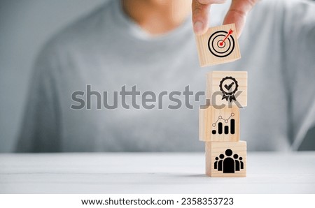 Hand presenting a wooden block cube with an icon, signifying the significance of company strategy development. Conceptual image of success and business goals.