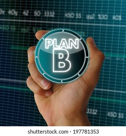 a hand presents digital round button with a plan b sign on it in front of a electronic data table from stock market