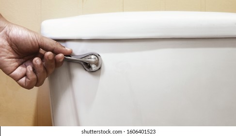 hand press and flush toilet for cleaning. concept of flushing away something with white toilet bowl. - Shutterstock ID 1606401523