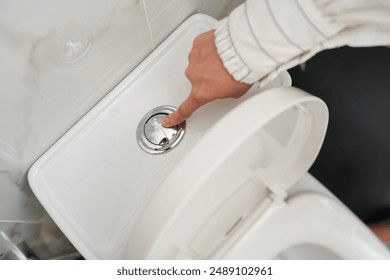 hand press the toilet button after using bowl in the bathroom - Powered by Shutterstock