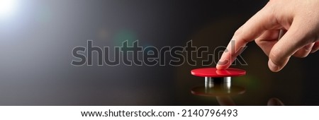 The hand presses the big red button. The concept of the threat of nuclear war. A threat to the world with a nuclear suitcase and a bomb. The hand presses the rocket launch button.