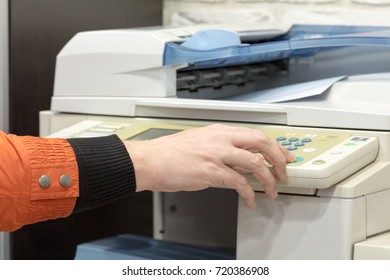 hand presses button in big multifunction printer