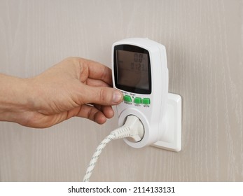 Hand presses button in wattmeter on wall, for measuring electricity costs in device, close-up - Shutterstock ID 2114133131