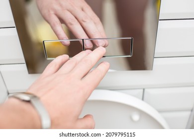 Hand presses a modern economical press for flushing clean water into the toilet, with two separate buttons.  - Shutterstock ID 2079795115