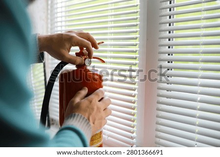 hand presses the trigger fire extinguisher available in fire emergencies conflagration damage background. 