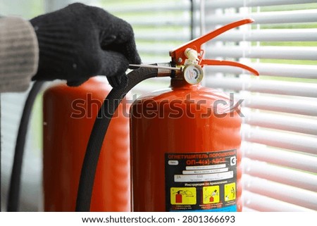hand presses the trigger fire extinguisher available in fire emergencies conflagration damage background. 