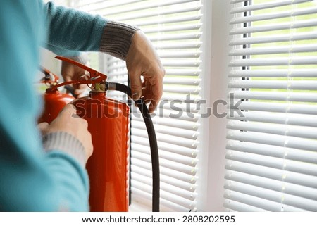 hand presses the trigger fire extinguisher available in fire emergencies conflagration damage background. 