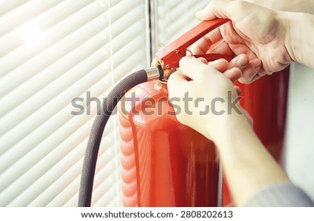 hand presses the trigger fire extinguisher available in fire emergencies conflagration damage background. 