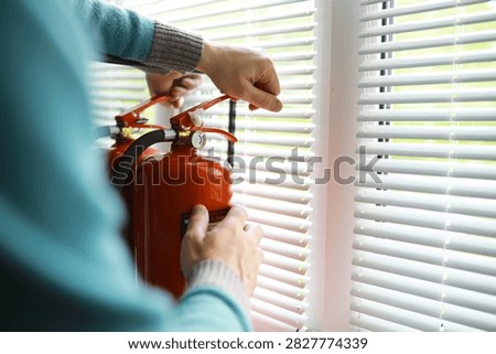 hand presses the trigger fire extinguisher available in fire emergencies conflagration damage background. 