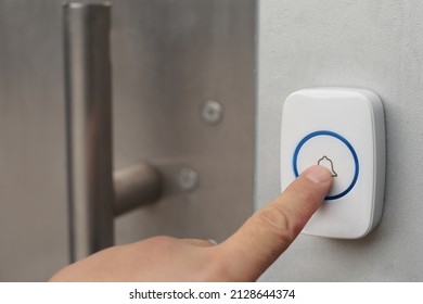 Hand pressing button on outdoor doorbell with an intercom 
